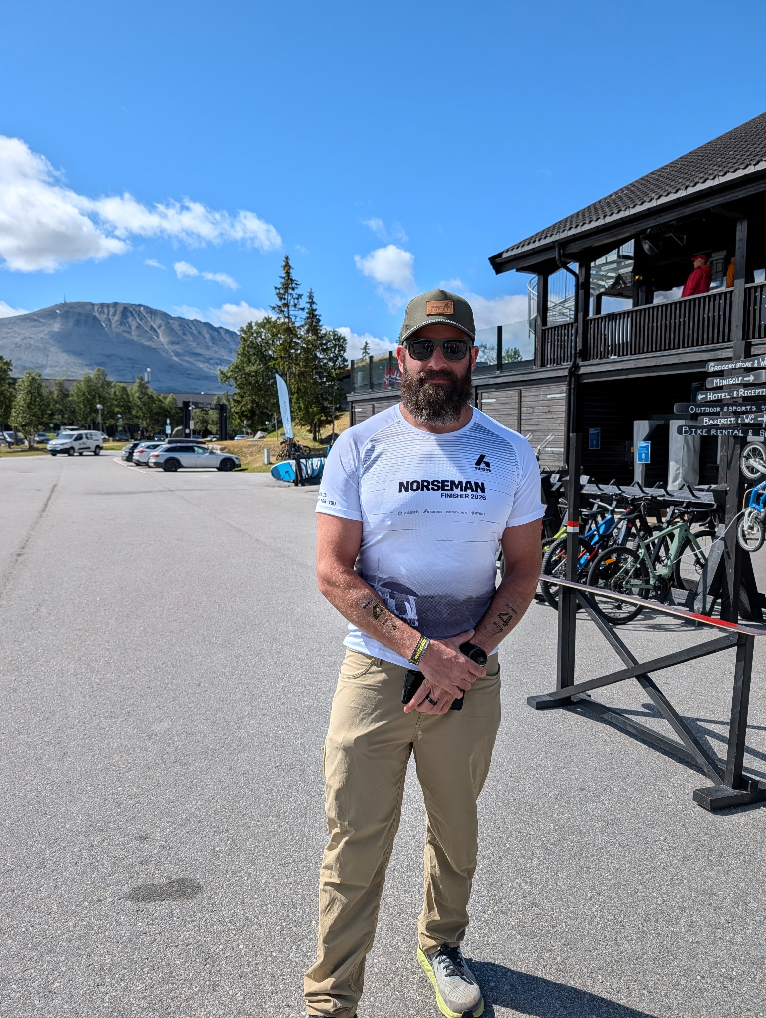 Ryan Cohen outdoors in his Norseman finisher shirt, with mountains behind him.